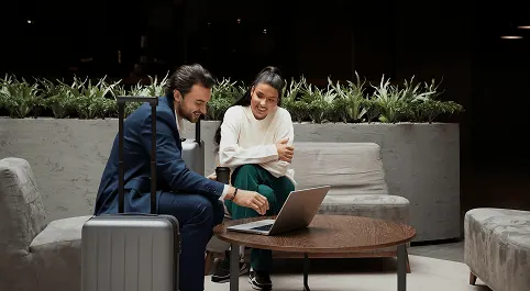 Deux collaborateurs de l'hôtellerie en réflexion autour d'un ordinateur dans un lobby